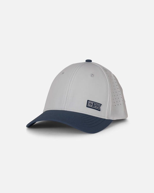 Introducing the Salty Crew Lowdown Snapback - Navy/Grey: a white baseball cap with a navy blue curved brim, featuring a small rectangular Salty Crew patch on the side. The cap is designed with laser-cut panels for enhanced breathability and includes ventilation holes on the back panels.