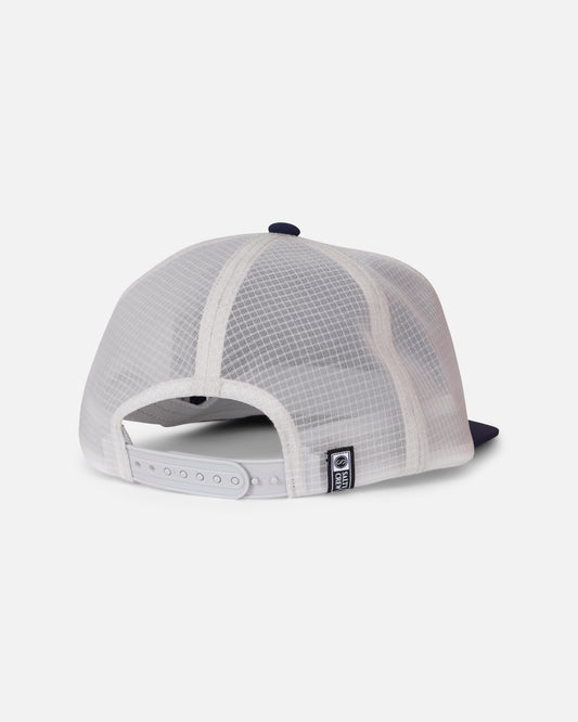 Back view of the Salty Crew Flagship Tech Trucker - Navy/Grey, an unstructured 5-panel trucker hat featuring white mesh, a navy blue brim, an adjustable snapback strap, and a small rectangular black and white patch near the closure, set against a plain light background.