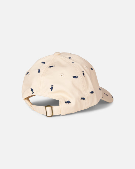 The Salty Crew Nice Catch Hat in Off White is an adjustable cotton cap featuring a brass buckle at the back and small navy shark silhouettes embroidered throughout the fabric.