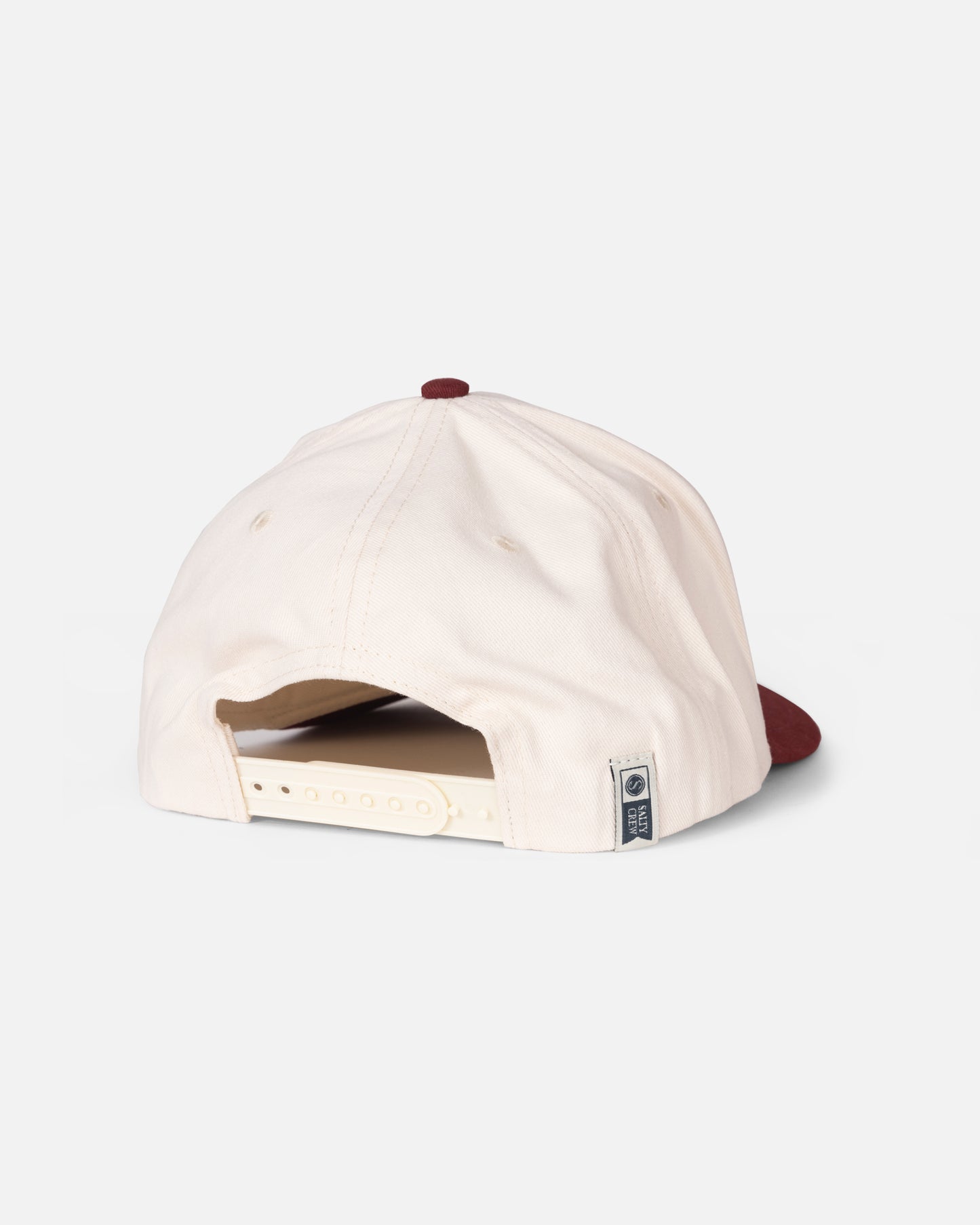 The Salty Crew Lured Trucker - Maroon is a cream-colored baseball cap with a maroon button and brim, displayed from the back. It features an adjustable snapback closure, a small fabric tag with the Salty Crew logo near the opening, and a moisture-wicking sweatband to keep you comfortable throughout the day.
