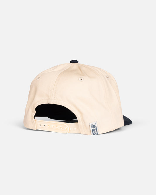 The Salty Crew Coordinates Snapback Hat in Off White/Navy, shown from the back on a white background, features a high crown, a cotton twill build, an adjustable strap, navy brim, and a small side fabric tag.