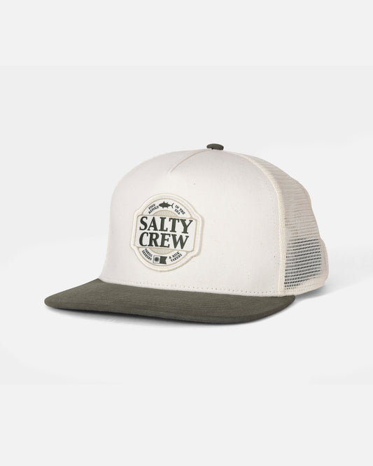 The Salty Crew Split Fill Trucker in Off White/Green is a 5-panel hat featuring a high crown, olive green mesh back, and a front patch displaying the Salty Crew logo. It offers an adjustable fit with a comfortable cotton snapback closure.