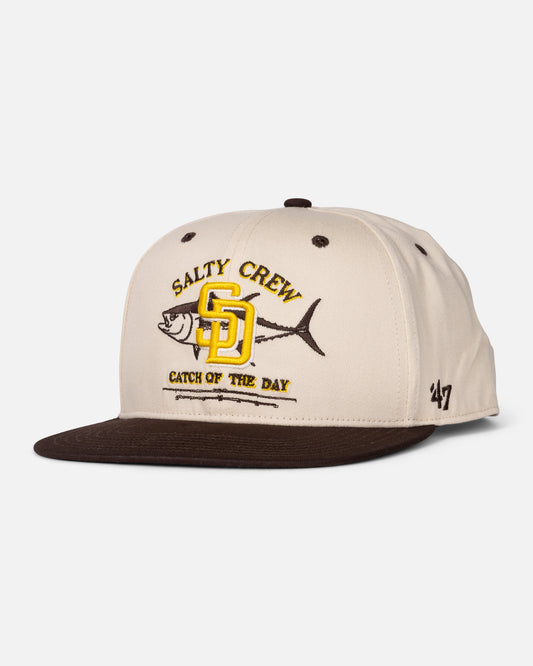 Introducing the Padres Catch of the Day Hat - Bone by Salty Crew: This unique limited edition snapback features beige and brown hues, “Salty Crew” and “Catch of the Day” text, a yellow SD logo inspired by classic San Diego Padres hats, an embroidered fish detail, a small ’47 logo on the side, and classic ’47 Brand Captain RL construction.
