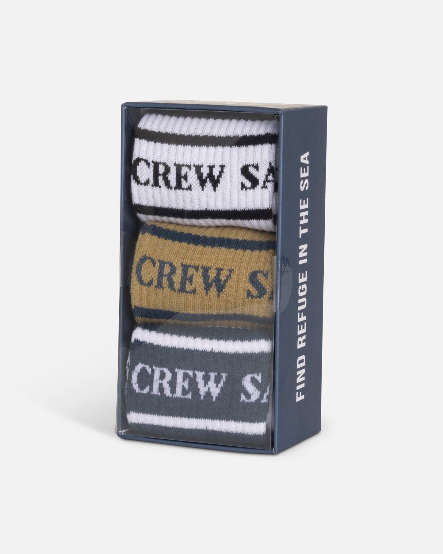 The Salty Crew Flagship 3-Pack Sock Box - Assorted includes three pairs of cotton blend crew socks (white, gold, black) with CREW SA on the cuffs, fits sizes 7-11. Box features "FIND REFUGE IN THE SEA" on the side.