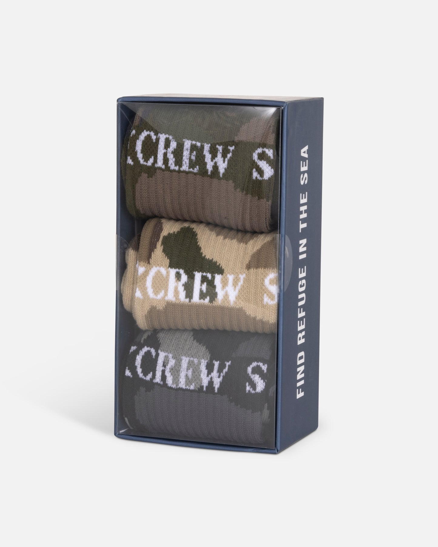 The Salty Crew Camo 3-Pack Sock Box - Assorted includes three pairs of cotton blend crew socks (size 7-11) in green, beige, and camo with white text. The clear box side reads: "FIND REFUGE IN THE SEA.