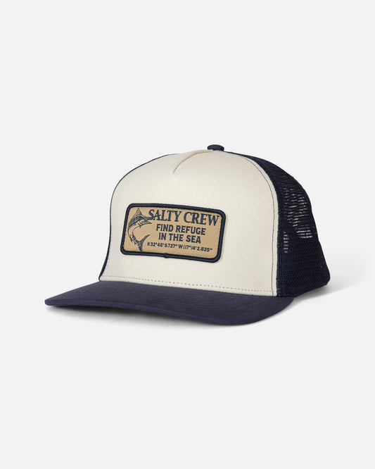 The Salty Crew Coordinates Trucker in Off White/Navy is a high crown, 5 panel cap featuring a mesh back and an adjustable cotton snapback for comfort. The front patch displays “SALTY CREW FIND REFUGE IN THE SEA,” geographic coordinates, and a fish illustration.