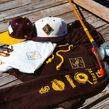 Salty Crew x Padres hats, tee, and sweatshirt sitting on dock.