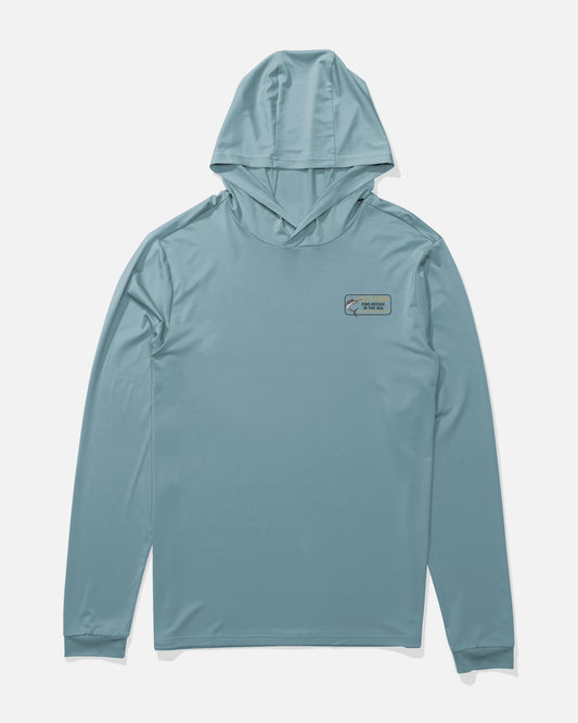 The Salty Crew Coordinates Hood Sunshirt in Hitch Blue is shown laid flat on a white background, featuring a small patch with a fish graphic and coordinates text on the left chest. Made from lightweight stretch fabric offering UPF 50+ sun protection, this long-sleeve hooded shirt is designed for comfort and performance both on and off the water.