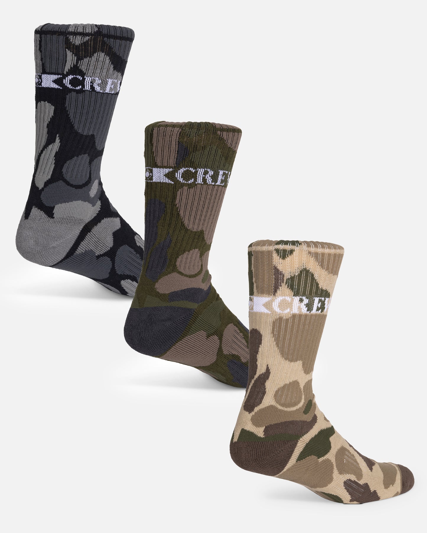 The Salty Crew Camo 3-Pack Sock Box - Assorted features three pairs of cotton blend crew socks in black, green, and tan camo designs with "CREW" in white at the top. Fits sizes 7-11; displayed on a plain light background.
