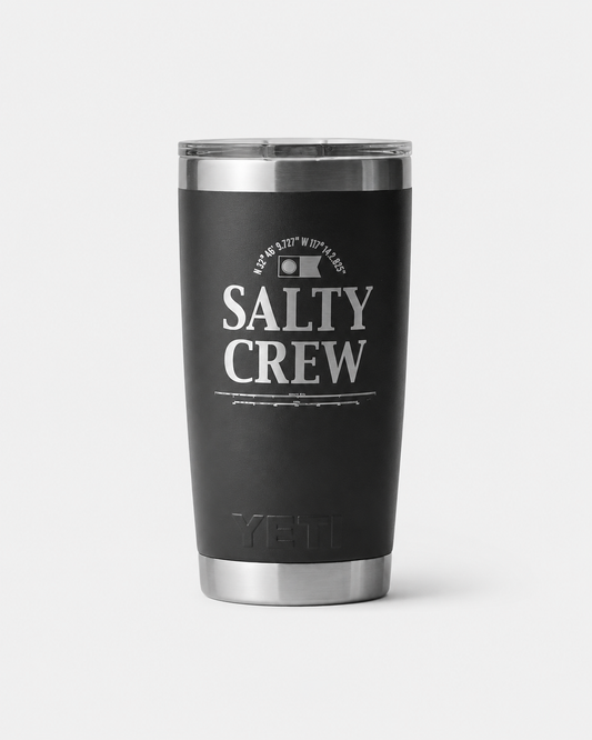 The Salty Crew Yeti x Salty Crew Tumbler 20 Oz in black is a vacuum-insulated stainless steel drinkware with a silver lid, featuring "Salty Crew" and a fish logo printed in white on the front.