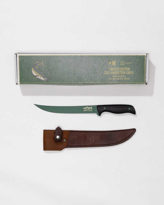The Salty Crew Leucadia x Salty Crew 8” Hamachi Fillet Knife, limited edition with a Detroit Diesel Green cerakote blade and black handle, comes boxed with a fish illustration, gold text, and includes a brown leather sheath.