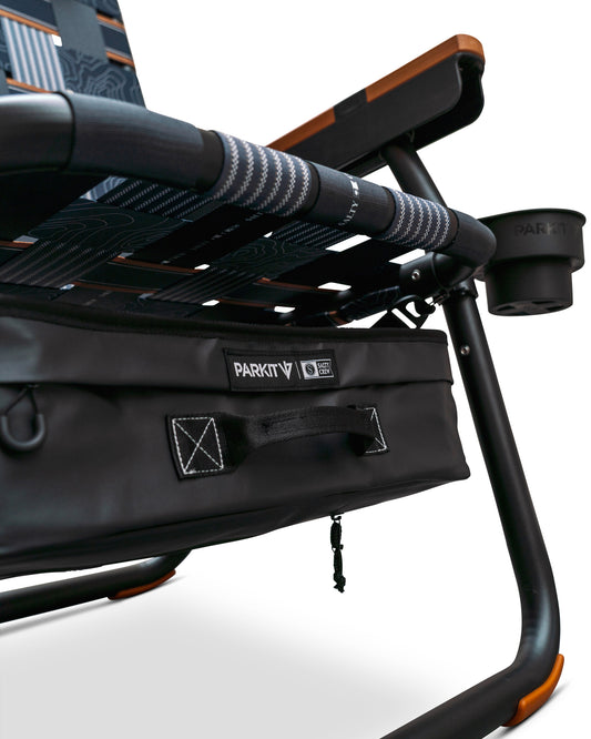 Close-up of the Parkit x Salty Crew Eclipse Recliner Chair by PARKIT Co. in black, featuring patterned fabric, a sturdy frame, attached storage pouch, integrated cooler, and a cup holder on the armrest.